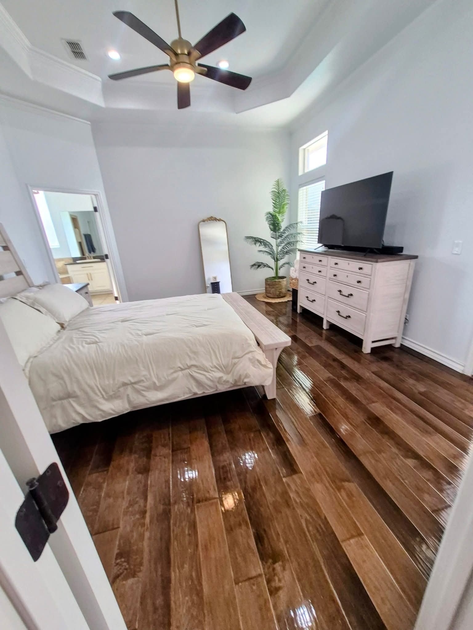 Clean master bedroom with ceiling fan and hardwood floors